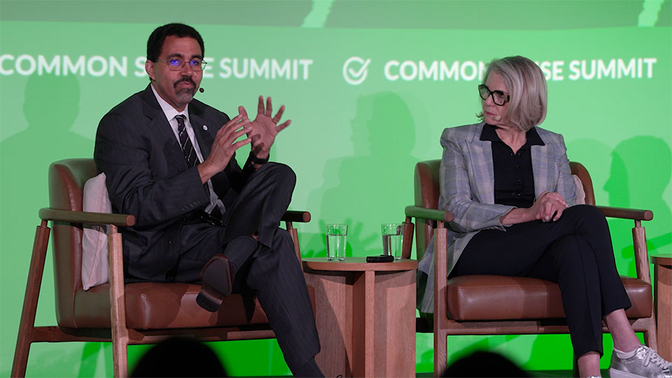 John King and Margaret Spellings seat on stage in front of green monitor