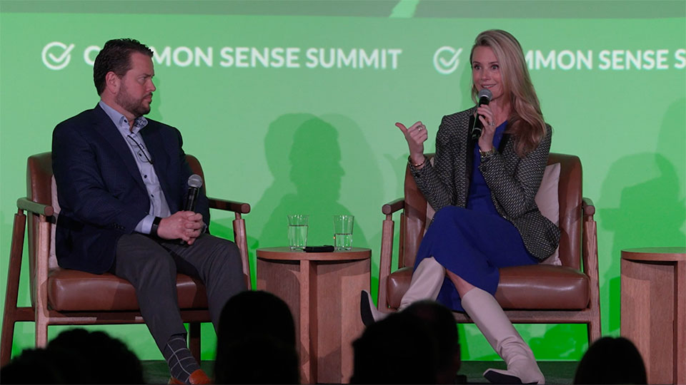 Bill Ready and Jennifer Siebel Newsom seated on stage in front of green background