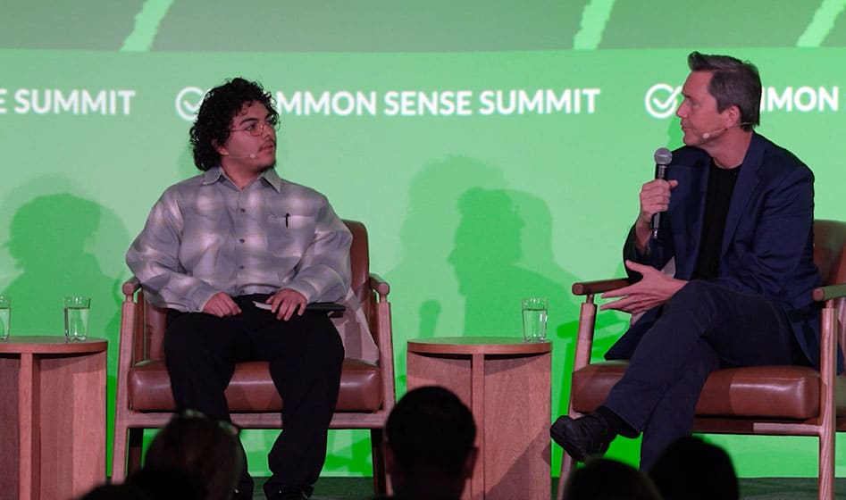Teen boy seated on stage next to Richard Reeves