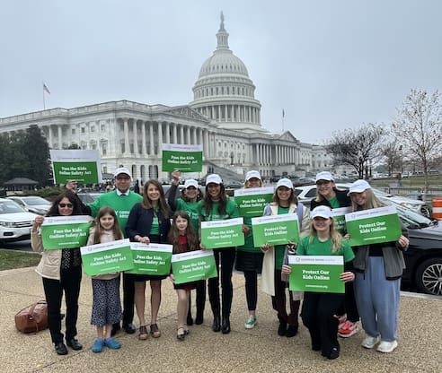 A crowd of people in green shirts in front of the capitol